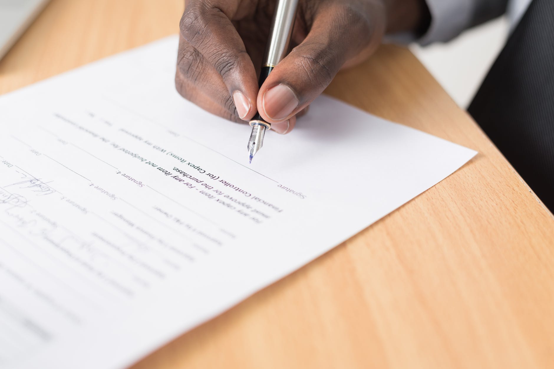 hand zet handtekening op papier met vulpen