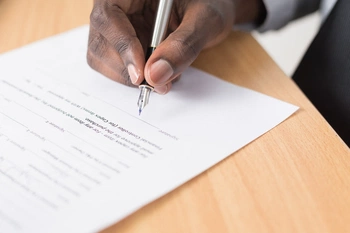 hand zet handtekening op papier met vulpen